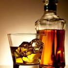 Un vaso de whisky con hielo y una botella