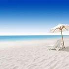 Una playa con un paraguas y una silla mirando hacia el océano azul