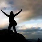 Una persona en la cima de una montaña con sus brazos levantados