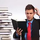 Un hombre con un traje de la lectura de un libro rascándose la cabeza al lado de una pila de libros