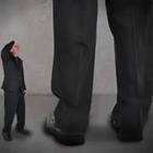 Una persona más pequeña con un traje al lado de la pierna de una persona más alta