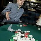 Una persona que se sienta en la mesa verde con juegos de cartas y fichas frente a ellos