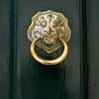 Una puerta verde oscuro con un objeto de oro en ella sosteniendo un anillo de oro