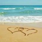 Una playa con dos corazones dibujado en la arena