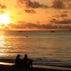 Dos personas mirando a la playa mirando la puesta de sol
