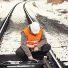 Un hombre en un chaleco naranja y casco blanco la fijación de una vía de ferrocarril