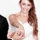 Una mujer en un vestido blanco, sosteniendo su mano con un anillo en ella