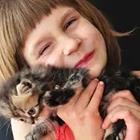 Una niña con un gato a su cara y sonriente