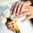 Dos personas Holidng manos con anillos en los dedos y las flores blancas están celebrando