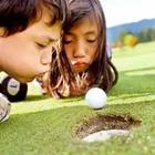 Niños que soplan en la pelota de golf