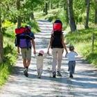Una familia caminando en un camino con los adultos que llevan mochilas