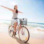 Mujer que monta la bicicleta en la playa